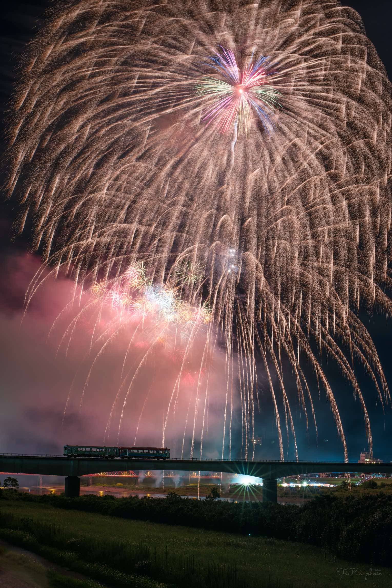 高知県四万十市を走る列車と夜空に上がる花火